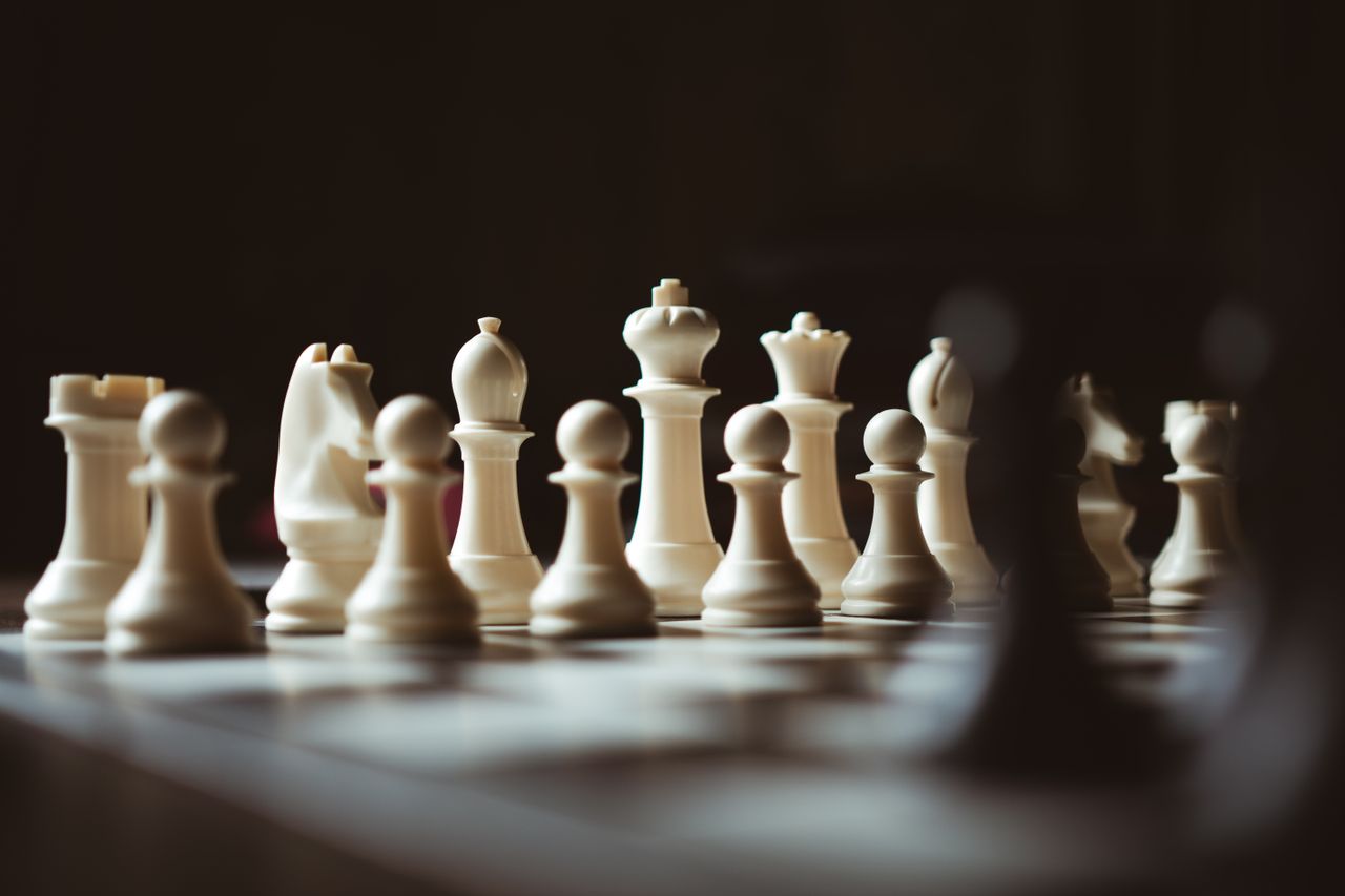Detailed close-up view of white chess pieces on a chessboard, highlighting strategy and focus.