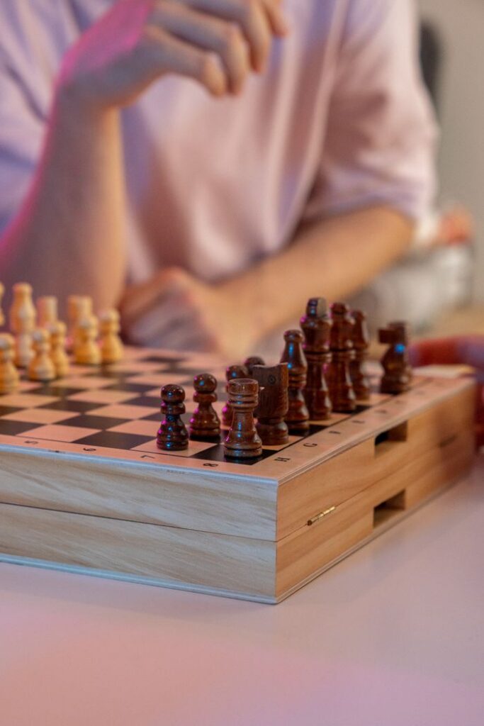 Mastering the First Impression: Your intriguing post title goes here Close-up of a chess match with wooden pieces on a chessboard, hands preparing for a move.